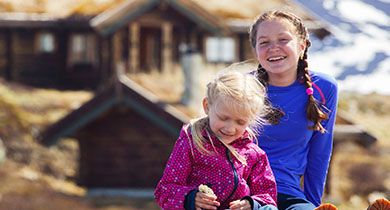 Jenter som sitter foran en hytte på fjellet