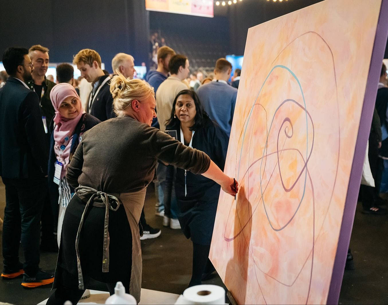 Kunstner maler abstrakt verk, omgitt av nysgjerrige tilskuere.