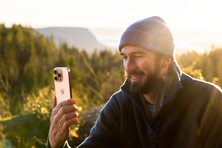 mann som sitter i skogen og facetimer med sin iphone 16 pro max