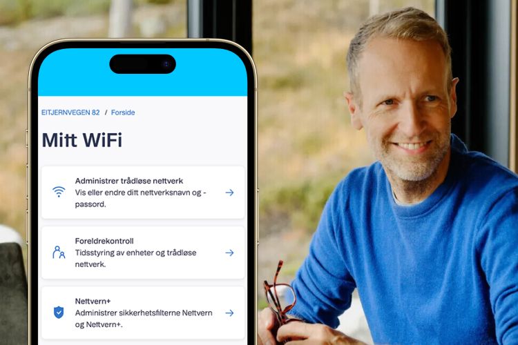 En smilende mann i blå genser ved siden av en mobilskjerm som viser Mitt WiFi-appen.