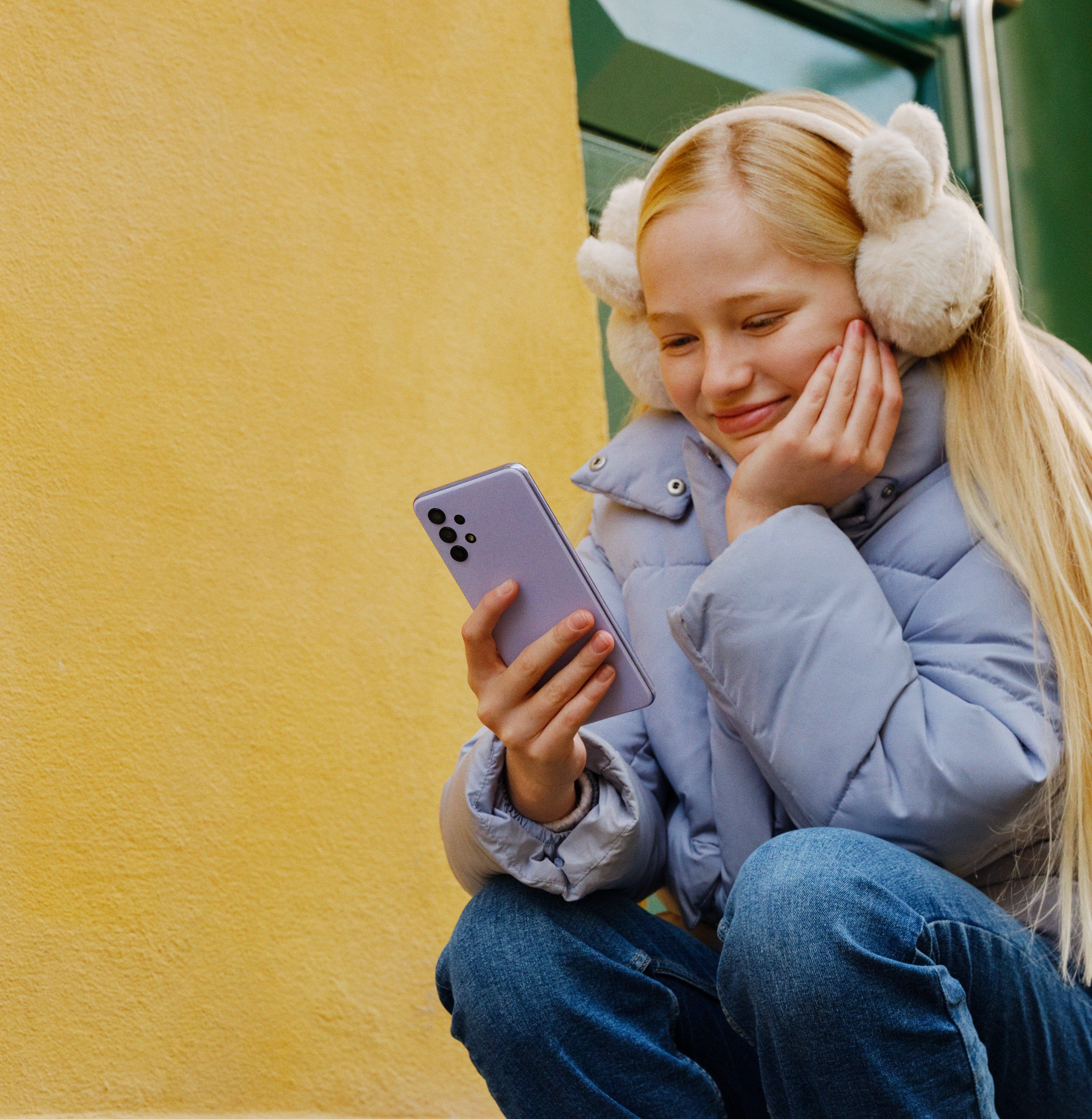 Jente som ser på mobilen og som har mobilabonnement for barn