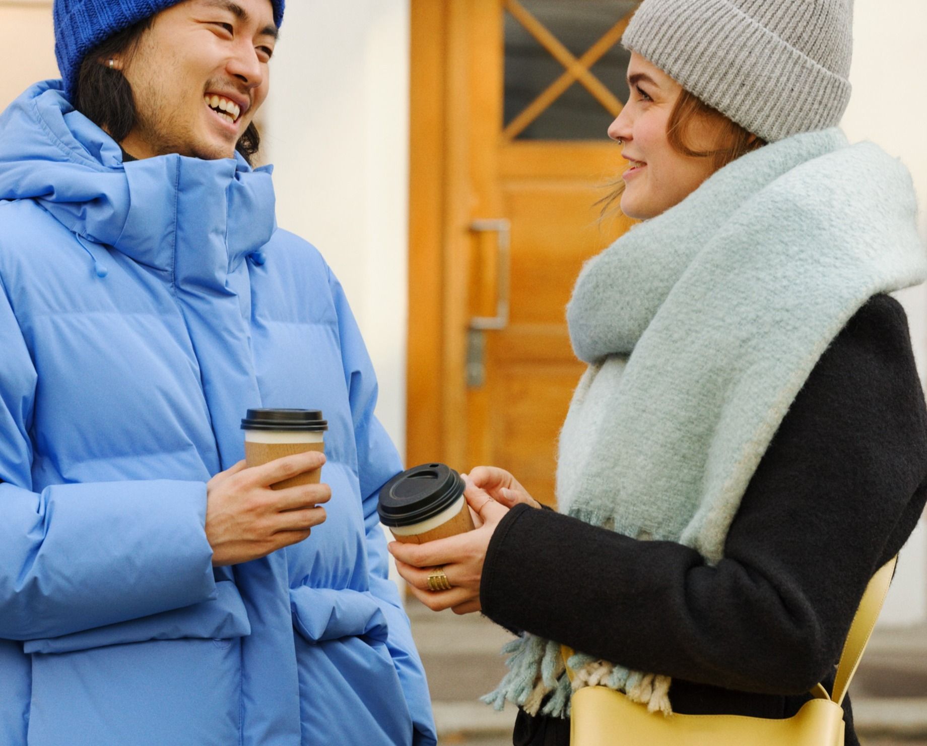 Kvinne og mann utendørs med kaffe og som har mobilabonnement for unge fra Telenor