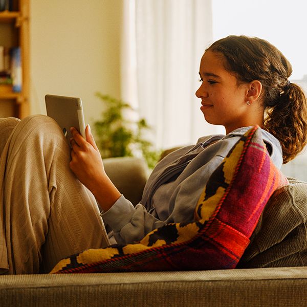 jente som sitter i sofaen og ser på en iPad