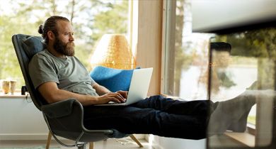 Mann sitter i stop og ser på laptop