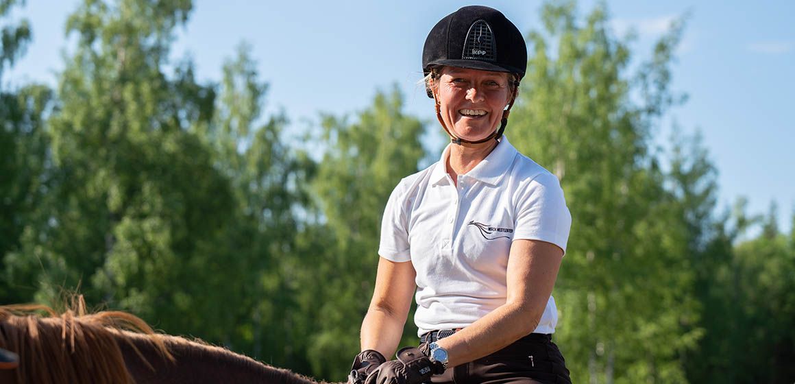 Norsk Hestesenter ansatt sitter på hesteryggen