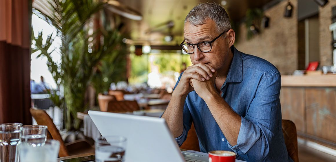 Mann med laptop på kafé sjekker bedriftens digitale verdier