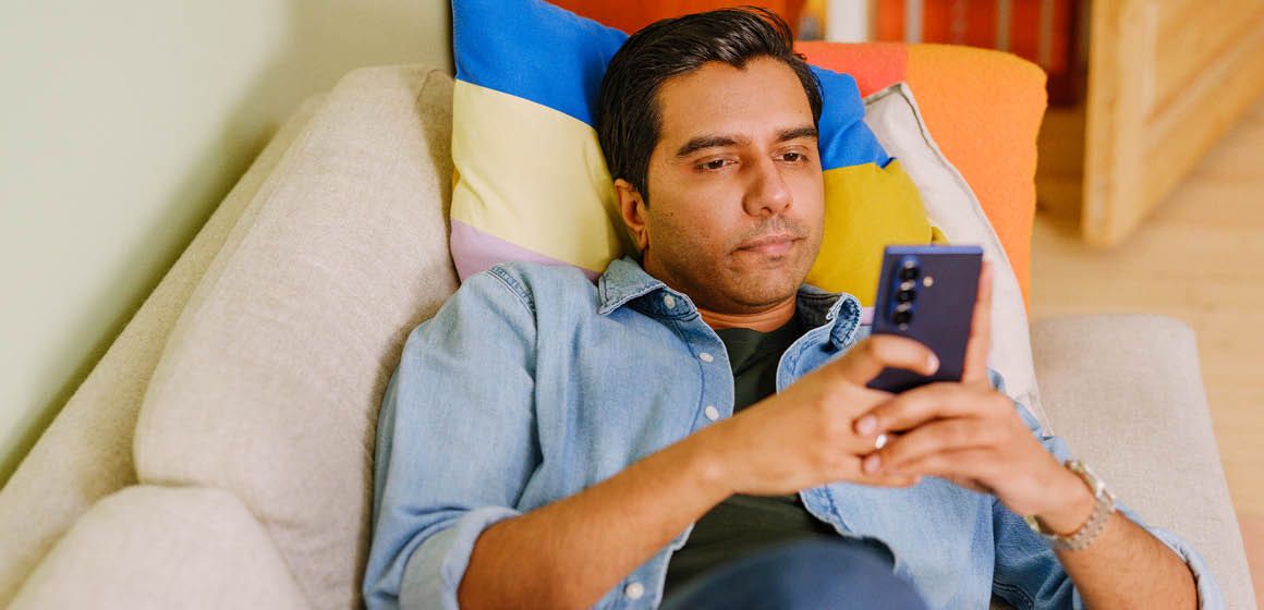 Person som ligger på en sofa og bruker en mobiltelefon