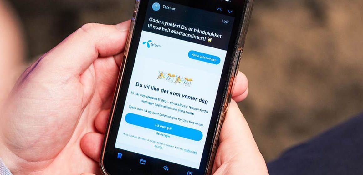Hånd som holder en mobil med en Telenor-melding om eksklusive fordeler