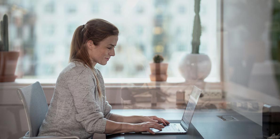 Dame på kontor som jobber på PC