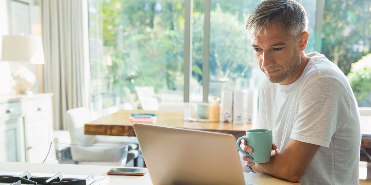 mann bruker egen mobil og pc til jobb