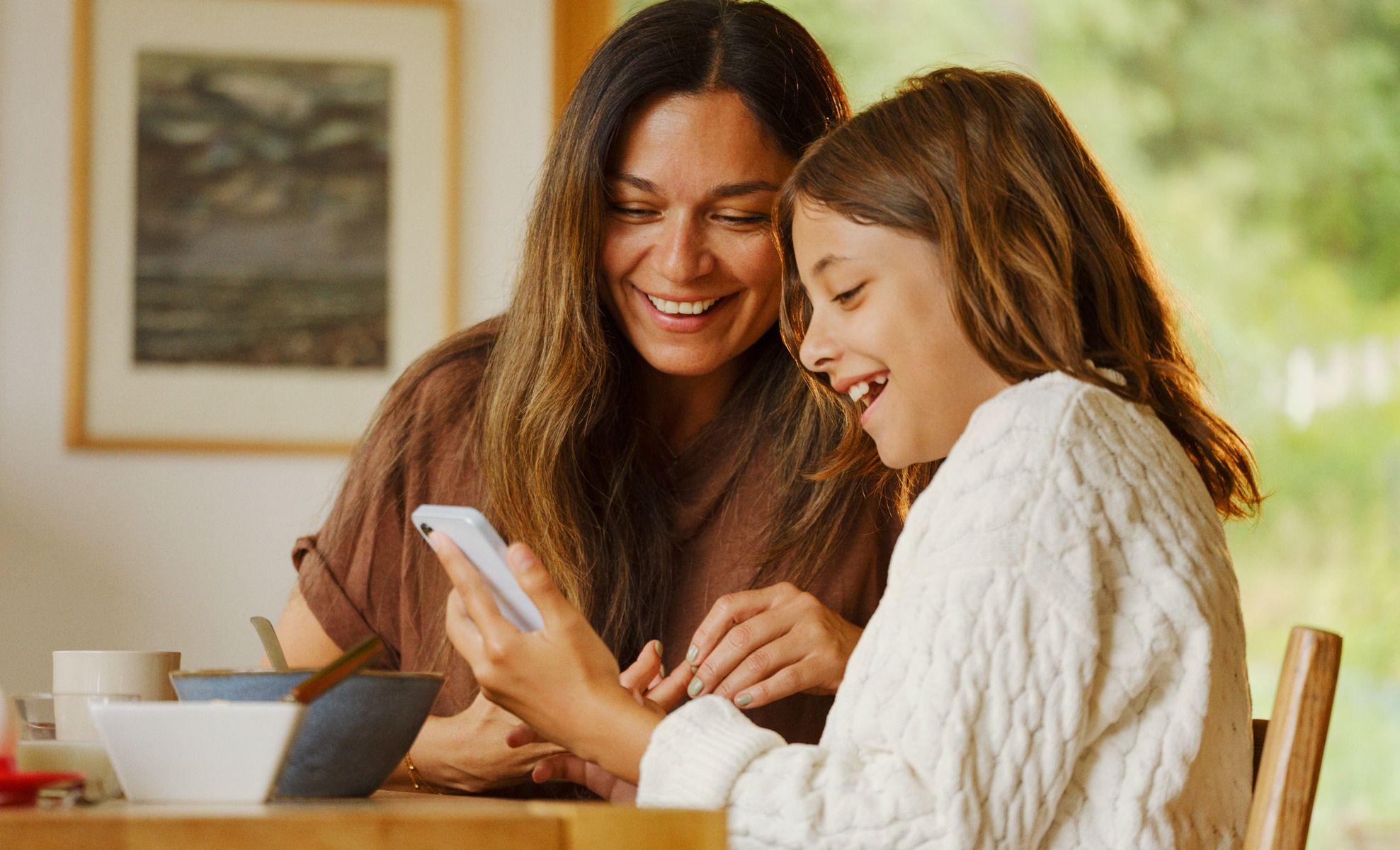To personer kledd i ullgensere ser på en telefon
