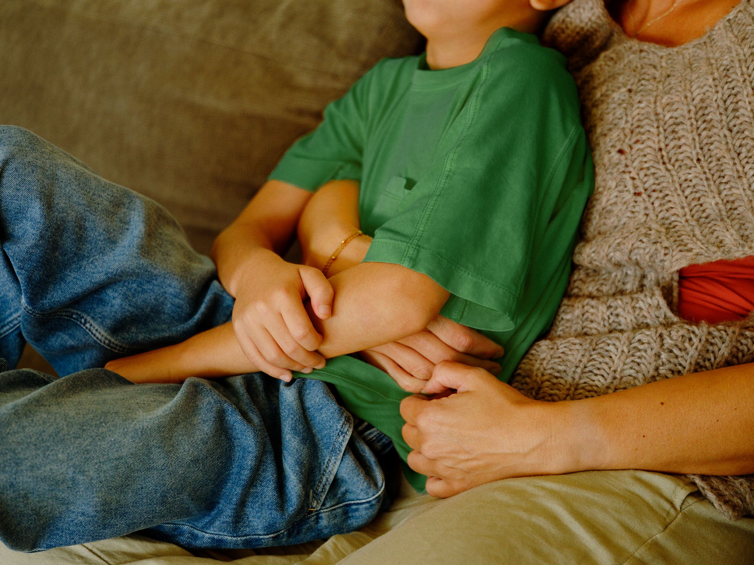 Et barn og en voksen sitter tett, iført grønn t-skjorte og strikkegenser