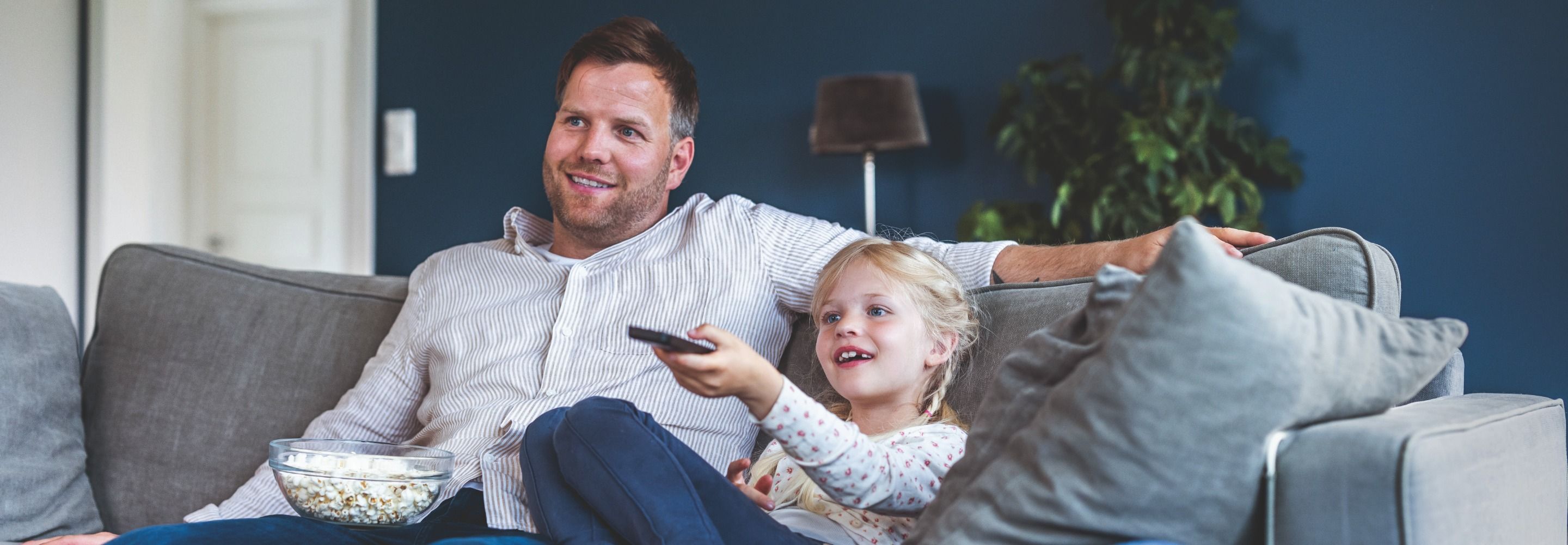 Far og datter som sitter i sofaen og ser på TV