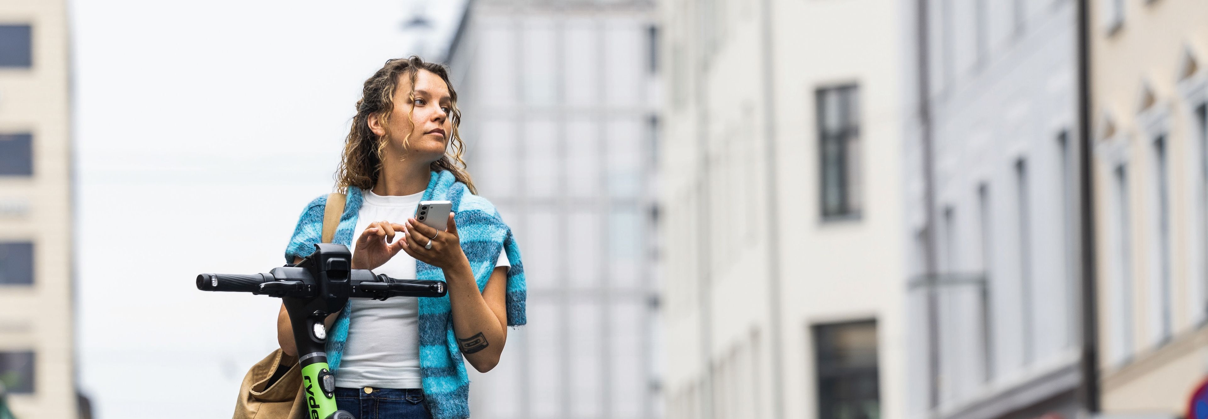 Person ved sparkesykkel ser på mobil med Telenor-dekning