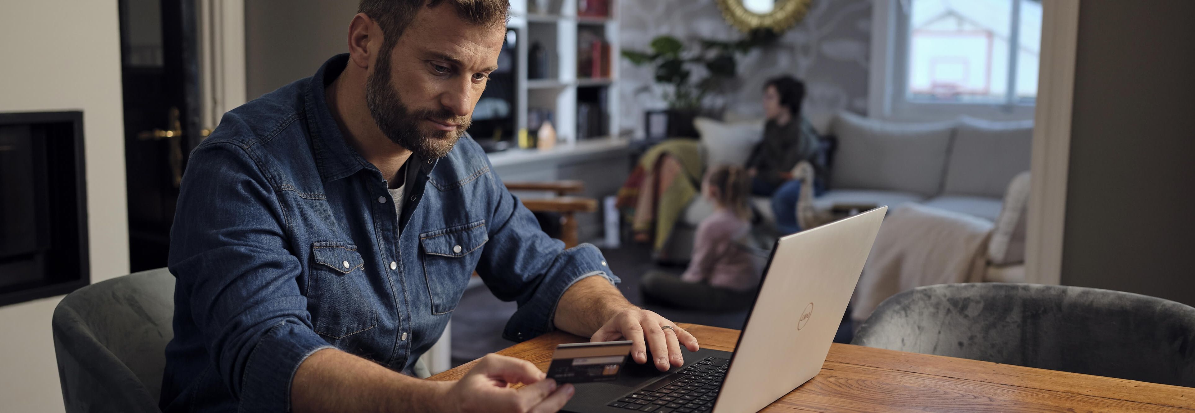 Mann som leser om svindelforsikring på laptop fra en kafé