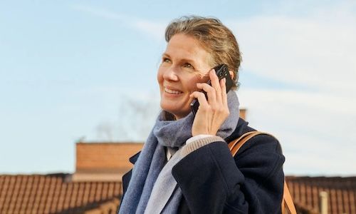 dame på strand, med mobil og abonnement fra Telenor