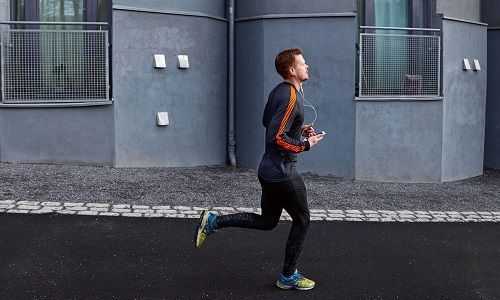 Mann som jogger med smartklokke i totalperspektiv fra siden