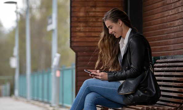 Dame på benk med mobiltelefon