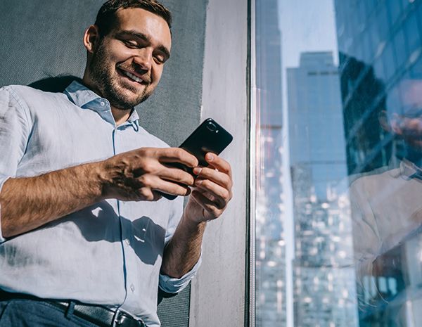 Mann bruker mobilen og smiler