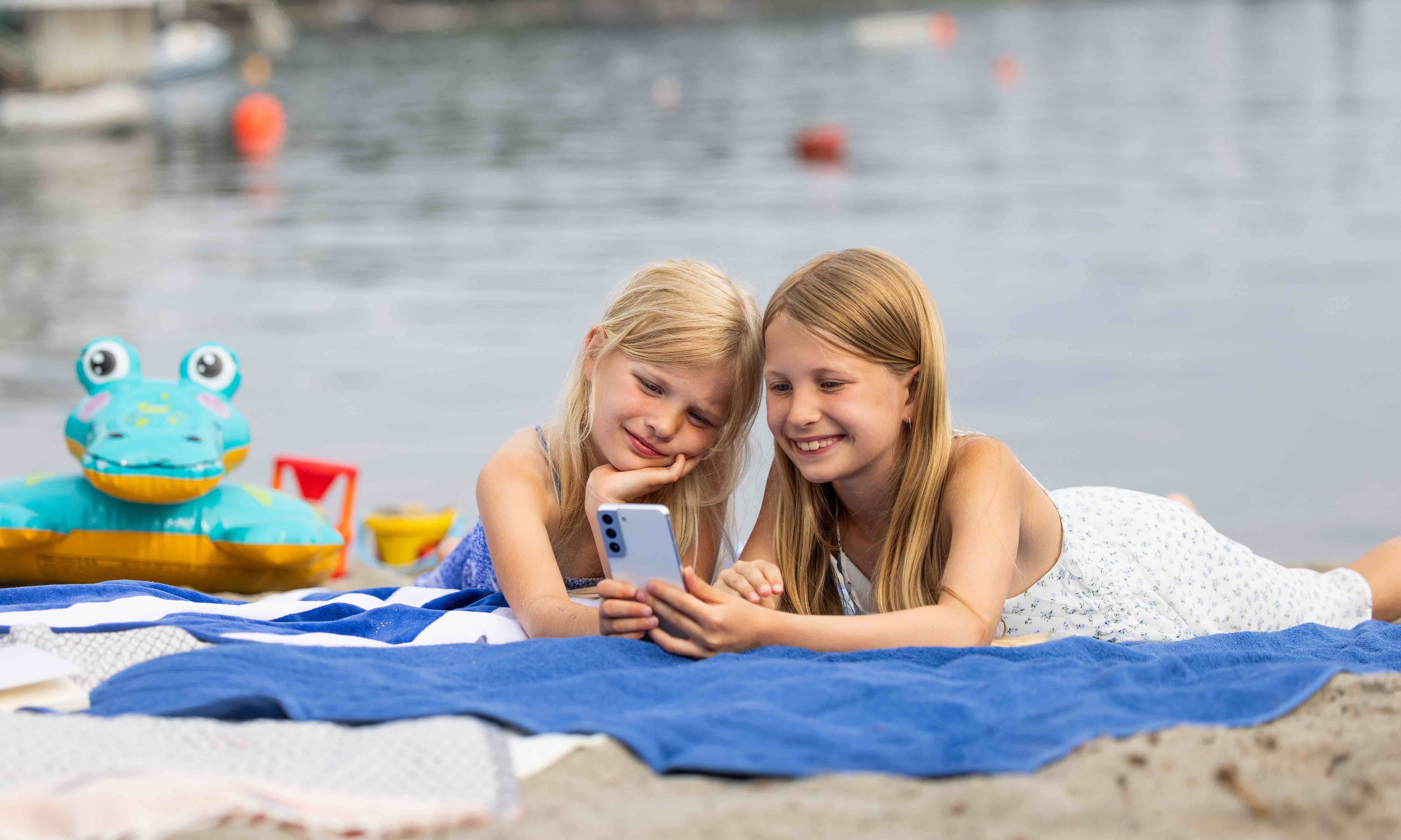 Mobilabonnement for familien: To jenter bruker data på stranden