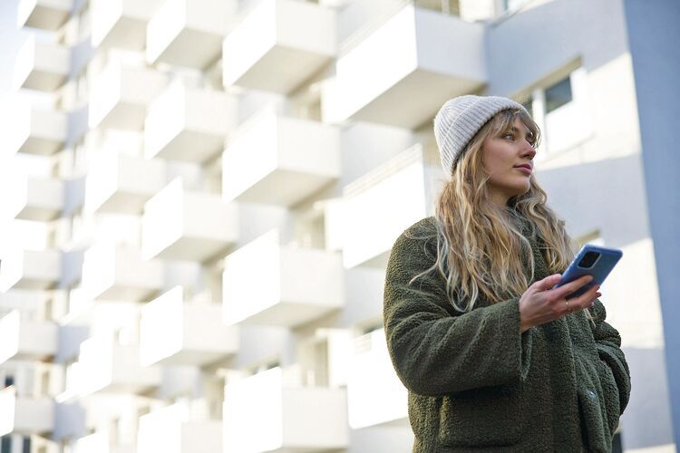 Ung kvinne med mobil i hånden som skal velge mobilabonnement fra Telenor