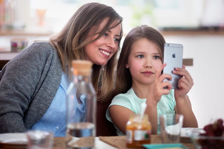 Mor og datter som ser på en mobil sammen