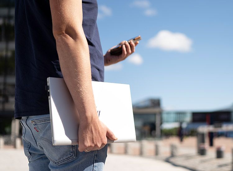 Mann med mobil og laptop sikret med Endepunktsikkerhet