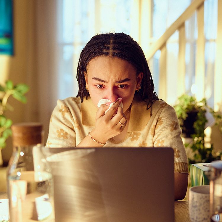 Dame sitter på laptop med pollenallergi
