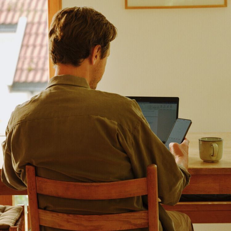 Mann som surfer på mobil og pc sett bakfra