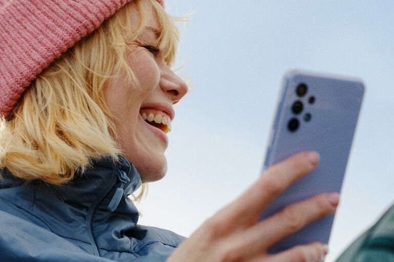 Kvinne med mobil under en blå himmel