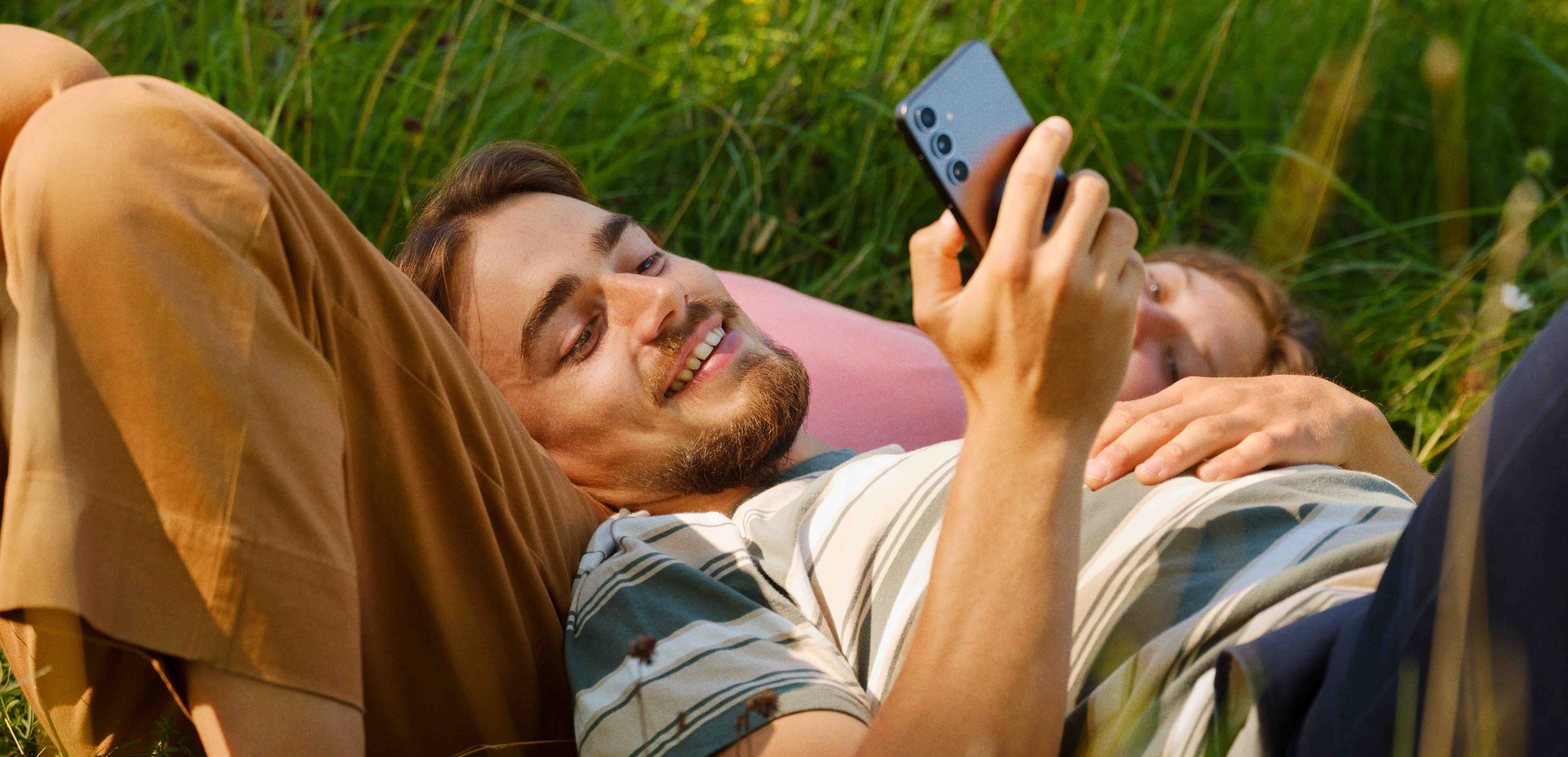 mann som ser på samsung-mobilen sin i parken